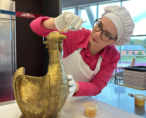 Confiseurin Svenja vergoldet die Schoko-Henne mit einem Pinsel